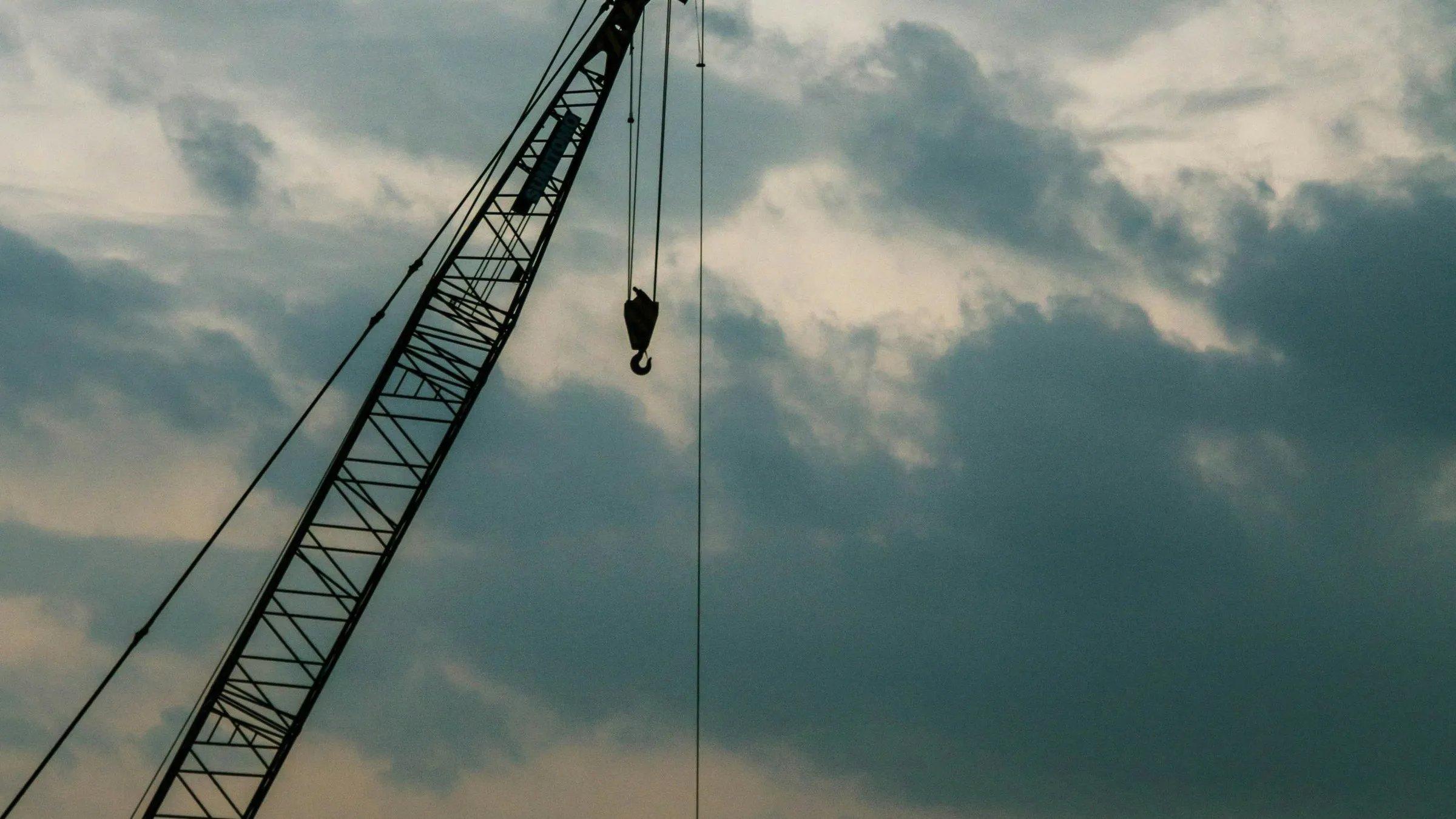 Crane boom and hook against the sky, used as an editorial image